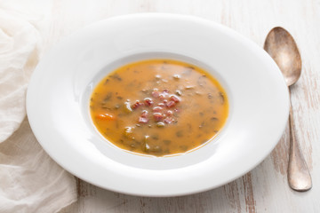 soup with smoked meat in white plate on wooden background