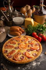 Pizza with sausages and tomatoes for a restaurant menu.