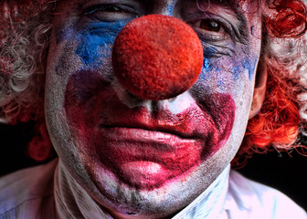 Close up of a sad, stressed, upset, crying clown with red nose. Dark and moody.