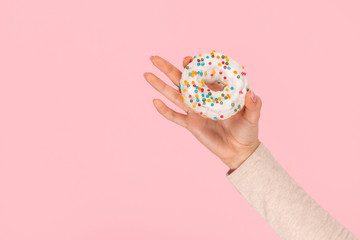 Crop hand demonstrating donut with sprinkles