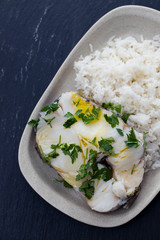 boiled perch with parsley and boiled rice on dish on ceramic background