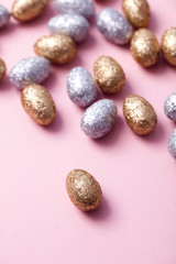 Gold and silver glitter easter eggs on a pastel pink background.