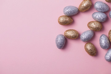 Gold and silver glitter easter eggs on a pastel pink background.