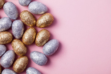 Fototapeta na wymiar Gold and silver glitter easter eggs on a pastel pink background.