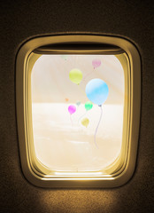 flight concept, colorful balloons above the clouds seen from window airplane.
