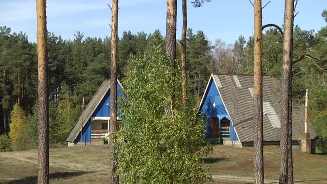 Wooden houses are in the forest. Wooden houses of triangular shape with a roof to the ground.