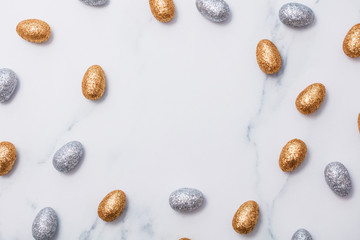 Gold and silver glitter easter eggs on a marble background