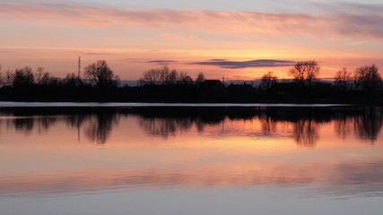 red sunset over the water of a village lake
