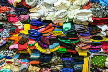 Fabric store. Warehouse with stacked colored rolls of fabrics for sewing.