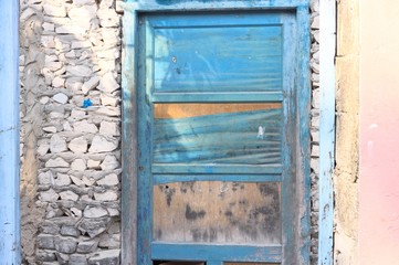 Blue wooden door in a stone wall of an abandoned pink house (Ari Atoll, Maldives)