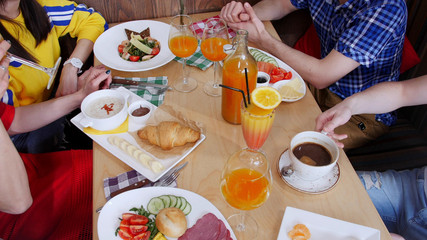Group of friends sitting in a cafe. Table full of different food and drinks