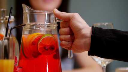 A couple sitting by table in a cafe. A man holding a jar handle