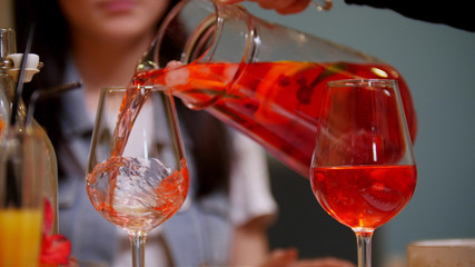 A couple sitting by table in a cafe. A man pours the drink in the glass