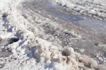 Ground covered with thawing snow and car trace