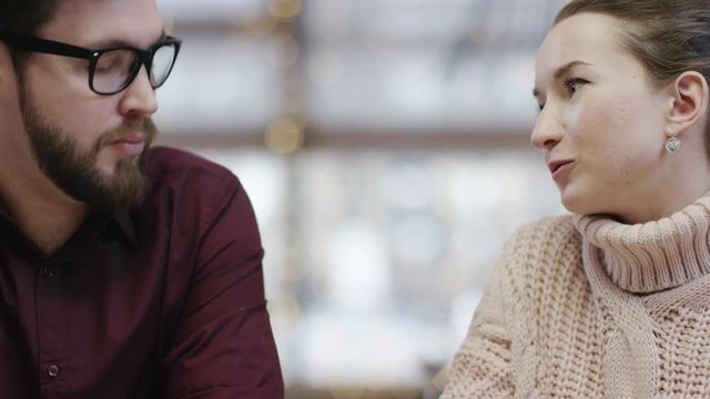 Adult man sitting with his girlfriend in restaurant and paying the bill by using NFC technology on his smartphone