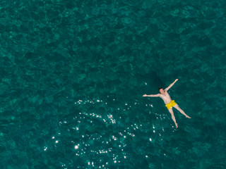 Obraz premium young adult man swimming on his back in blue azure water