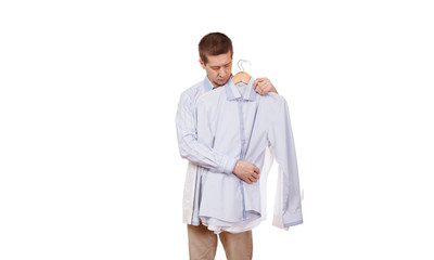 The man considers a coat hanger with clothes on a white background