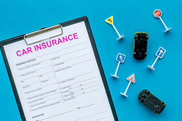 Car insurance concept with form, car toys on blue background top view