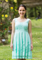 Fototapeta premium portrait of young woman in dress near roses in a garden