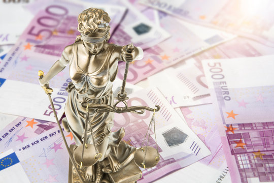 Eine goldene Justitia Figur steht auf vielen 500 Euro Geldscheinen. Konzeptionelles Bild zum Thema Gericht und Geld. Lens Flares.