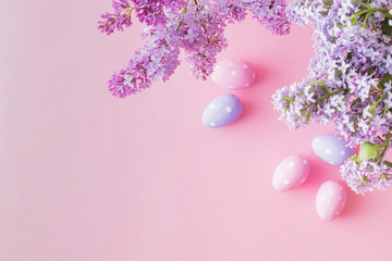 Flat lay composition with branches of lilac and easter eggs on a pink background