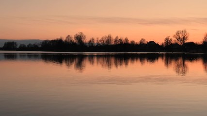 red sunset over the water of a village lake