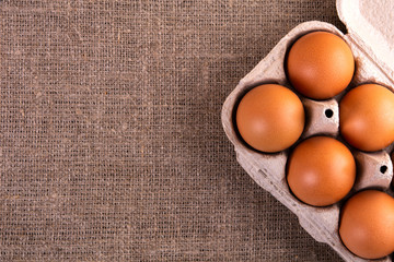 raw chicken eggs in a basket on a jute cloth background