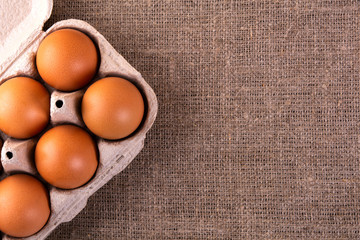 raw chicken eggs in a basket on a jute cloth background