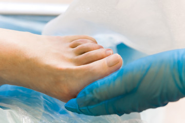 The doctor holds the patient's leg to hands