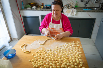 italian woman makes orecchiette pasta home made on wood board step by step with traditional way of...