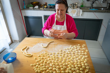 italian woman makes orecchiette pasta home made on wood board step by step with traditional way of...