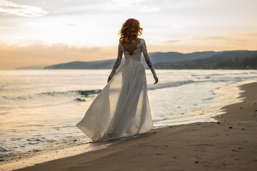 The red-haired bride. Wedding. Sea. Sandy beach. Sunset.