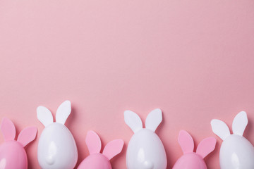 Fototapeta na wymiar Easter eggs with bunny ears on a pastel pink background