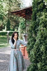 Attractive young smiling woman in cute summer dress with flower print in the garden