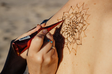 The image of the back of the girl decorated with henna tattoo. Mehndi mandala.