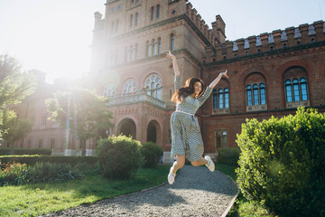 Fototapeta na wymiar Happy attractive young woman jumping with sunny backlight on the garden
