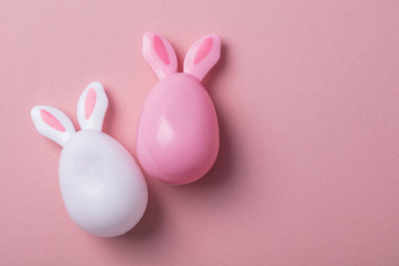 Easter eggs with bunny ears on a pastel pink background