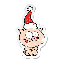 cheerful sitting pig distressed sticker cartoon of a wearing santa hat