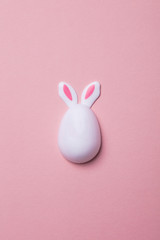 Easter egg with bunny ears on a pastel pink background