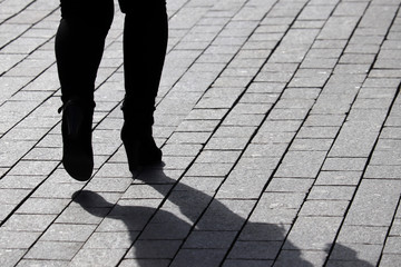 Silhouette and shadow of woman walking down the street. Girl on high heels, concept of female...
