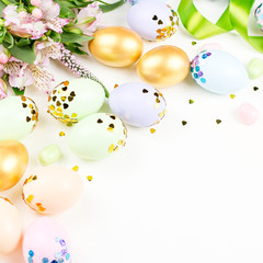 Festive Happy Easter background with decorated eggs, flowers, candy and ribbons in pastel colors on white. Copy space