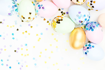 Festive Happy Easter background with decorated eggs, flowers, candy and ribbons in pastel colors on white. Copy space