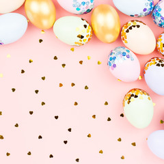 Festive Happy Easter background with decorated eggs, flowers, candy and ribbons in pastel colors on pink. Copy space