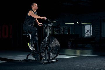Fototapeta na wymiar Male using air bike for cardio workout at cross training gym.