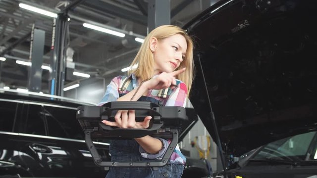 Beautiful blond girl concentrated on working with digital tablet PC at repair shop. Fast diagnostic