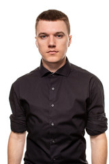 Obraz premium Handsome young man in a black shirt is making faces, while standing isolated on a white background