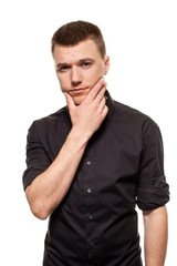 Handsome young man in a black shirt is making faces, while standing isolated on a white background