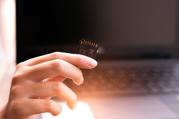 memory card on hand and Laptop background .