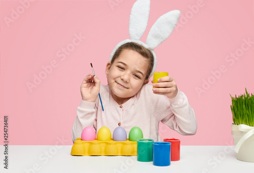 Content child girl with eggs and paints 