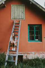 woman in front of brick wall on a ladder